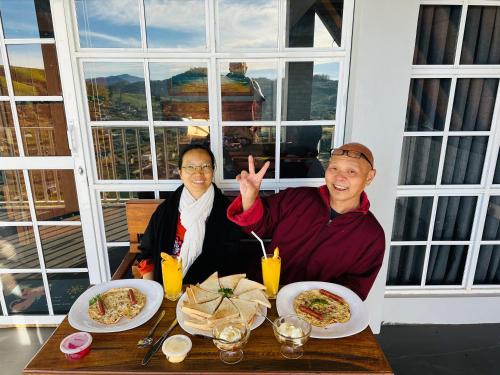 two men sitting at a table with plates of food at Cabin 7000 feet Nuwaraeliya in Nuwara Eliya