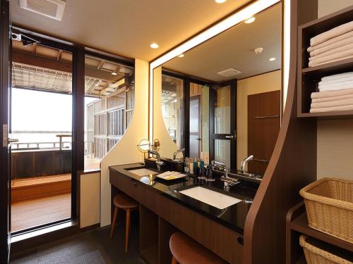 a bathroom with a sink and a large mirror at Arima Onsen Taketoritei Maruyama in Kobe