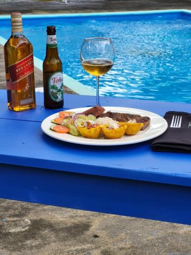 a plate of food and a glass of wine next to a pool at Hotel Museo El Ceibo in San José del Sur