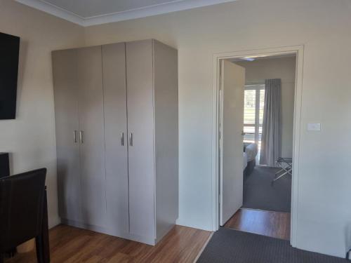 a living room with white cabinets and a bedroom at Australian Homestead Motor Lodge in Wagga Wagga