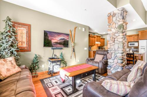 a living room with a couch and a stone fireplace at Treetops Ski Luxury Townhouse in Big White