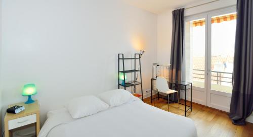 um quarto com uma cama branca e uma varanda em Appart' Zola em Lyon