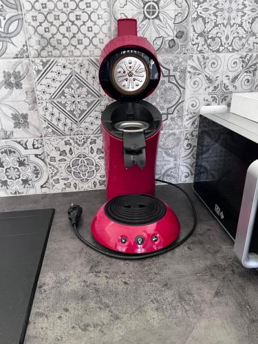 un mixeur rouge avec une horloge en haut dans l'établissement Appart calme à la mer, à Équihen-Plage