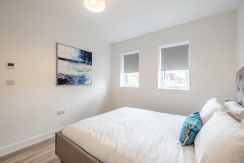 a white bedroom with a bed and two windows at ENTR - Modern Apartments in Windsor in Windsor