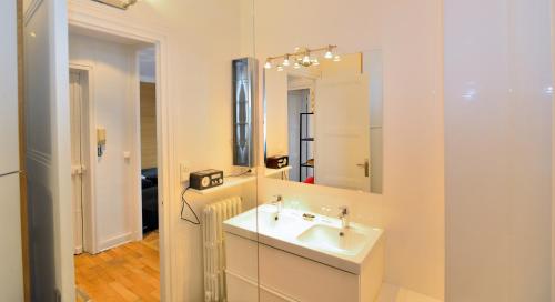 uma casa de banho branca com um lavatório e um espelho em Appart' Zola em Lyon