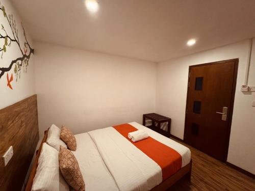 a bedroom with a bed with an orange and white blanket at CityRest Fort in Colombo