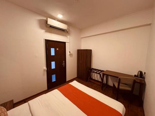a bedroom with two beds and a table and a window at CityRest Fort in Colombo
