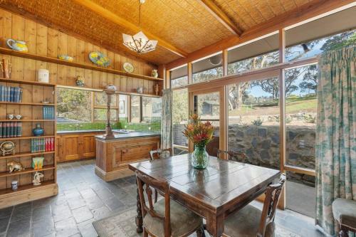 a dining room with a table and some windows at Rustic Cottage in Waitpinga
