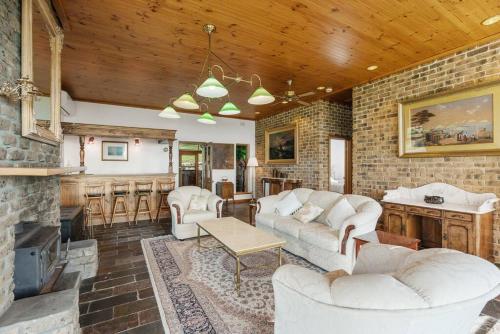 a living room with white furniture and a brick wall at Rustic Cottage in Waitpinga