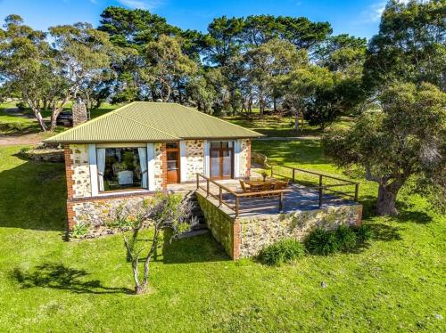 a small cabin in a field of grass with trees at Rustic Cottage in Waitpinga
