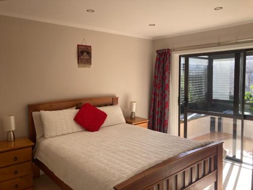 a bedroom with a bed with a red pillow on it at Joe & Mary's Comfy homestay room in Auckland