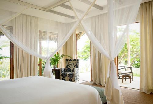 a bedroom with a bed and a large window at Qambani Luxury Resort in Michamvi