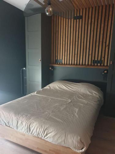 une chambre avec un lit blanc avec une tête de lit en bois dans l'établissement Studio quartier Boulingrin Reims, à Reims