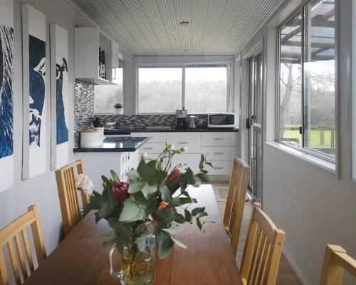a kitchen with a table with a vase of flowers on it at Cherswood Farm in Balbarrup