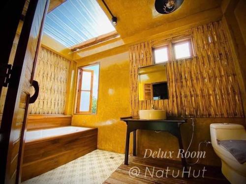 a bathroom with a tub and a toilet and a window at Natu Hut Farm Stay & Cafe' Chiang Mai in Ban San Pa Sak (1)