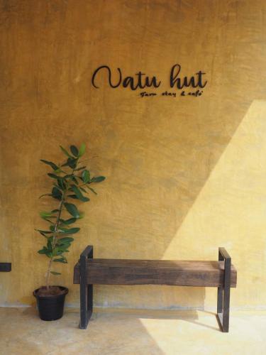 a bench sitting in front of a wall with a plant at Natu Hut Farm Stay & Cafe' Chiang Mai in Ban San Pa Sak (1)