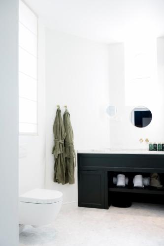 a white bathroom with a toilet and a sink at Hotel des Brasseurs in De Haan