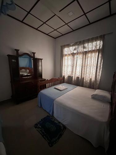 a bedroom with two beds and a dresser and a mirror at Fourcoock Villa in Kosgoda
