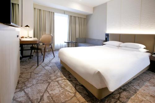 a hotel room with a large white bed and a desk at The Cypress Mercure Hotel Nagoya in Nagoya