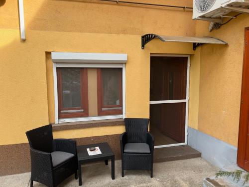two chairs and a table in front of a building at Szahara Vendégház in Kerekegyháza