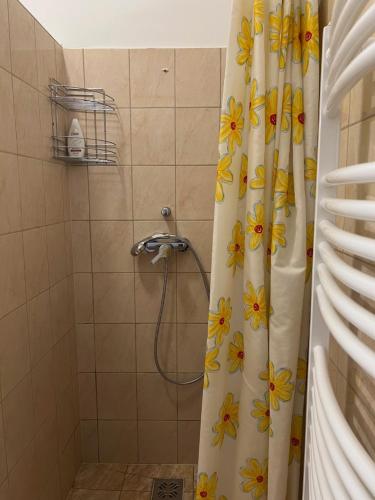 a shower curtain with yellow flowers on it in a bathroom at Szahara Vendégház in Kerekegyháza