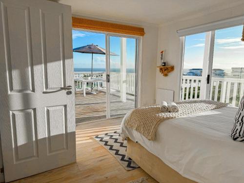 a bedroom with a bed and a balcony with an open door at Villa Bandarra in Yzerfontein