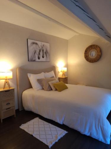 une chambre avec un grand lit blanc avec deux lampes dans l'établissement Maison de village médiéval surplombant les méandres de la loire, à Saint-Maurice-sur-Loire