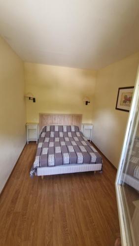 a bedroom with a bed in a room with wooden floors at Charmant t2 idéal Curiste 1min à pied de la cure thermale in Le Boulou