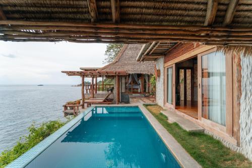 a house with a swimming pool next to the ocean at View Point Resort in Koh Tao