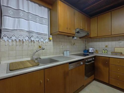 a kitchen with wooden cabinets and a sink and a window at Klea's House Skopelos in Skopelos Town