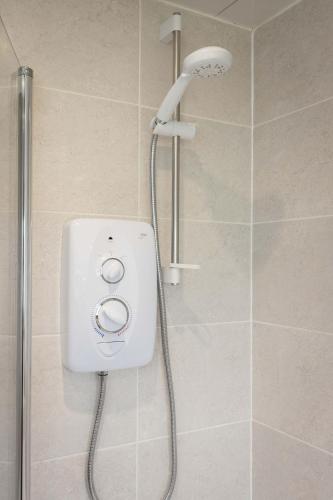 a shower with a white shower head in a bathroom at 20 mins to Edinburgh 3 bedroom detached family house Wi-Fi Parking in Fife
