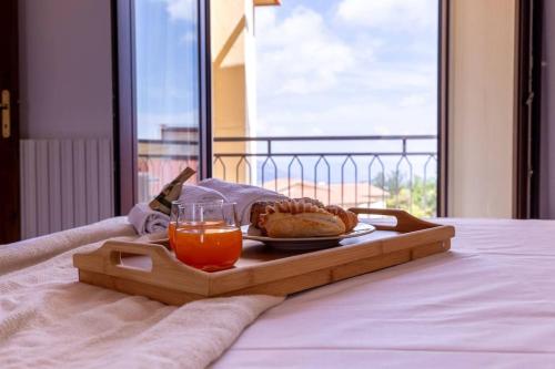 a tray with a plate of food and orange juice on a bed at Appartamento Confortevole, Wi-Fi & Colazione Free in Lanusei