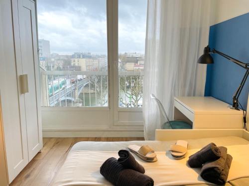 - une chambre avec un lit, des chaussons et une fenêtre dans l'établissement Le FRIENDLY, proche PARIS, à Villeneuve-la-Garenne