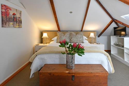 a bedroom with a bed with a vase of flowers on a table at Centre-Ville Guest House in Franschhoek