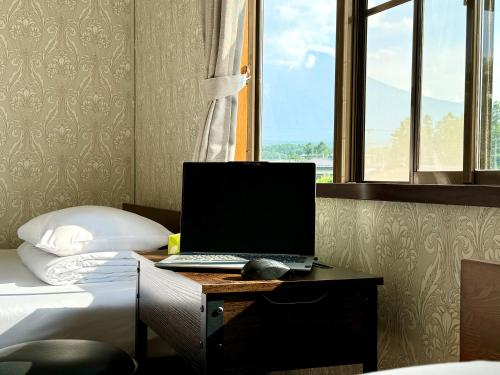 a laptop computer sitting on a desk next to a bed at HOEI villas Fujisan全景 富士山 河口湖中心区 in Fujikawaguchiko