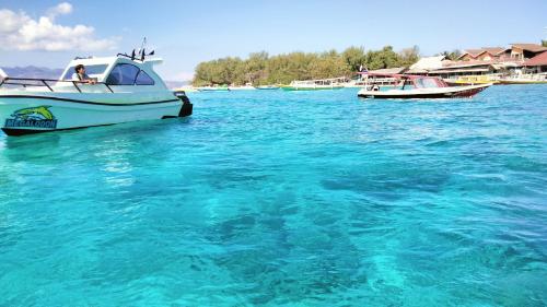 a white boat floating in the blue water at Sea Breeze Villas - Gili Air, Lombok in Gili Air