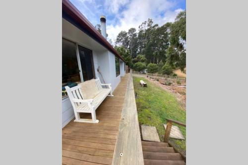a porch of a house with a bench and a dog at Fully fenced, wrap around decks, water on 3 sides in Lunawanna