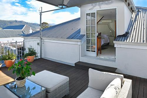 a balcony with a couch and a bed on a house at Centre-Ville Guest House in Franschhoek