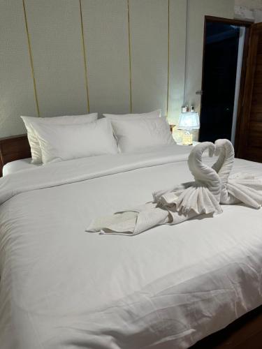 a white bed with a swan towel on it at Service Apartment Lampang Room101 ใจกลางเมืองใกล้กาดกองต้า in Lampang