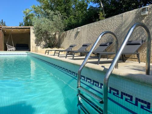 - une piscine avec des chaises longues à côté d'un mur dans l'établissement La maison en couleurs 3 étoiles, avec piscine, à Vedène