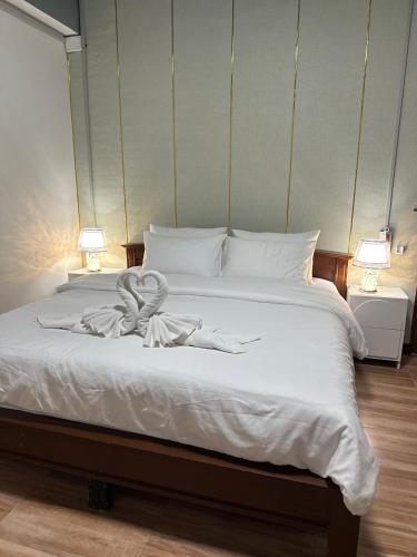 a bed with white sheets and a towel on it at Service Apartment Lampang Room101 ใจกลางเมืองใกล้กาดกองต้า in Lampang