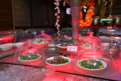 a buffet with plates of food in plastic domes at SkyCity Hotel Gurgaon in Gurgaon