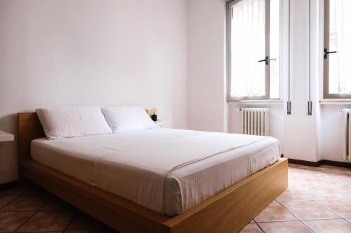 une chambre avec un lit avec des draps blancs et une fenêtre dans l'établissement Flora Inn, Paglia 2 - Nel cuore del centro città, à Bergame