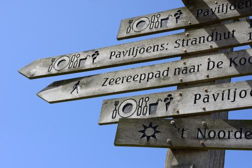 a wooden sign with arrows pointing in different directions at Aangenaam Texel Familie Bungalow in De Koog