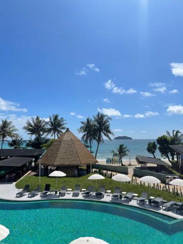 ein Swimmingpool mit Stühlen und Sonnenschirmen und das Meer in der Unterkunft Kai Bae Beach Resort Koh Chang in Ko Chang