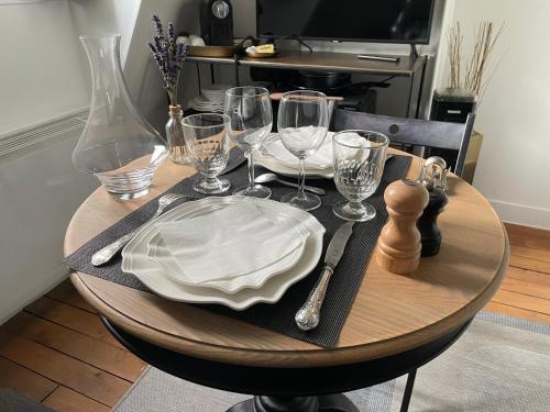- une table en bois avec une assiette et des verres à vin dans l'établissement Studio cosy 17e Arc de Triomphe et champs Élysées, à Paris