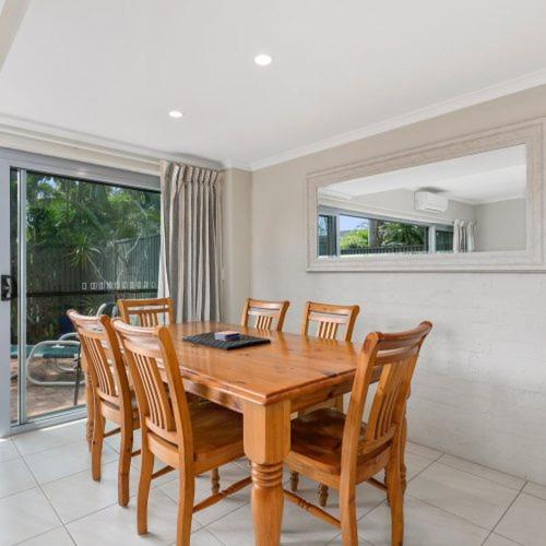 a dining room with a wooden table and chairs at Le Court Villas in Noosa Heads