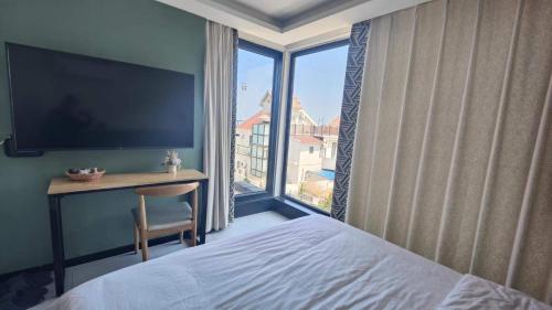 a bedroom with a bed and a desk and a large window at 威海蜂舍民宿 in Weihai