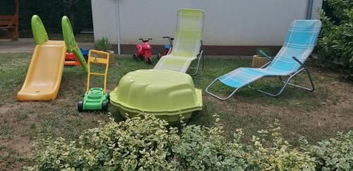 a group of plastic chairs and chairs in a yard at Levendula Apartman Berekfürdő in Berekfürdő