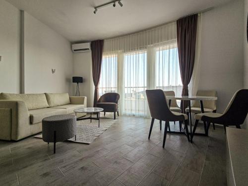 una sala de estar con un sofá, una mesa y sillas en Juzni Horizont Apartments, en Sutomore